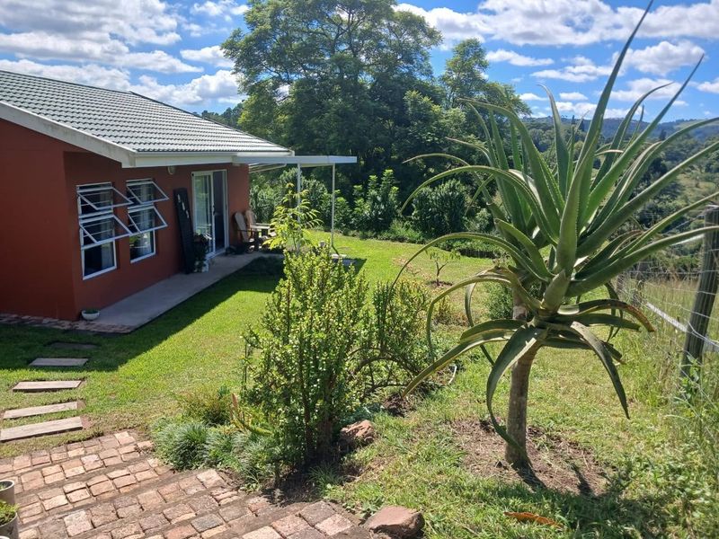 A view of the rear exterior of the property featuring a well-maintained garden, paved pathway, and access to the home via sliding glass doors.