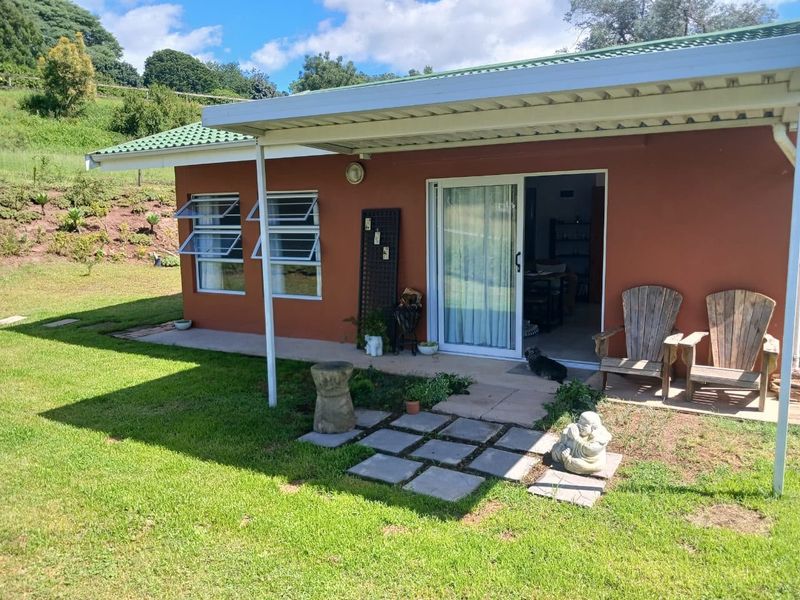A covered patio area featuring a sliding glass door entrance, louvre windows, and direct access to the surrounding garden space.