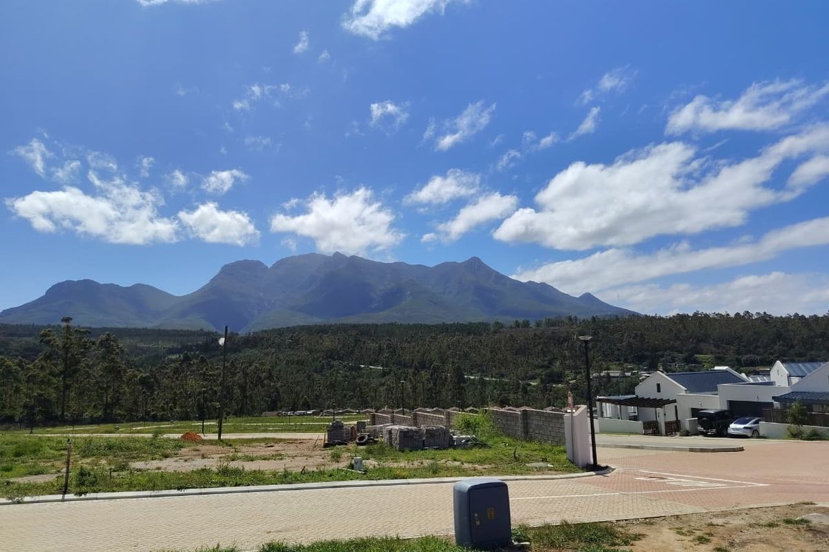 A scenic view of the surrounding mountain range and landscape from a residential estate street.