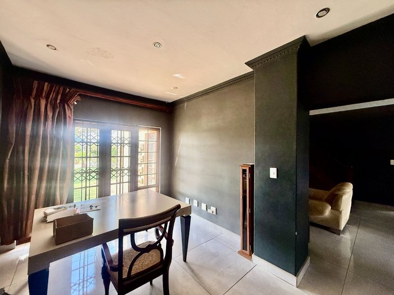 A living area featuring tiled floors, recessed lighting, crown molding, and a sliding door with security gate leading to the exterior.