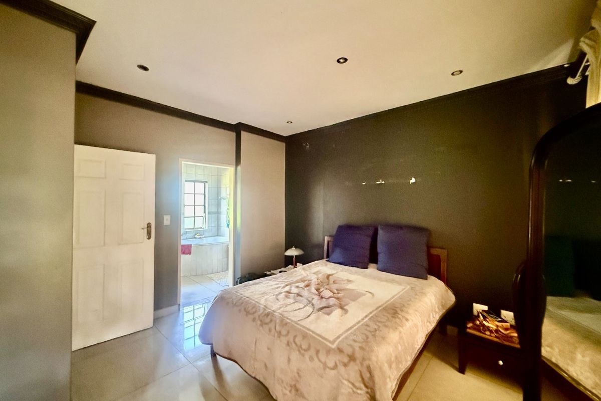 A bedroom featuring tiled flooring, recessed downlighting, and direct access to an en-suite bathroom.