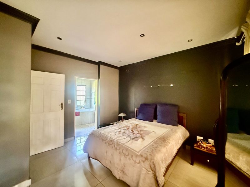 A bedroom featuring tiled flooring, recessed downlighting, and direct access to an en-suite bathroom.