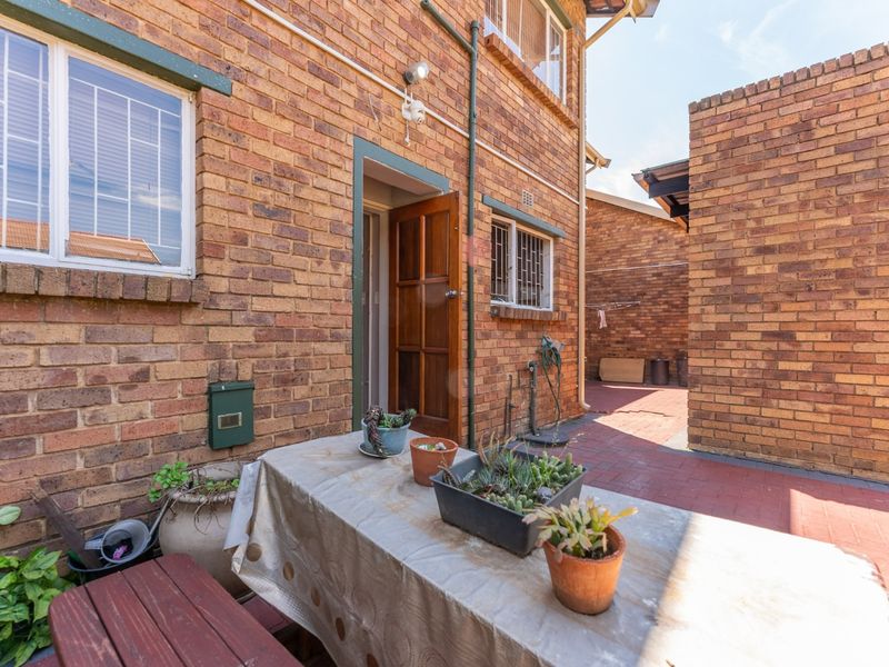 A rear courtyard area featuring face brick walls, paved flooring, and secure window bars, providing a functional outdoor space for the townhouse.