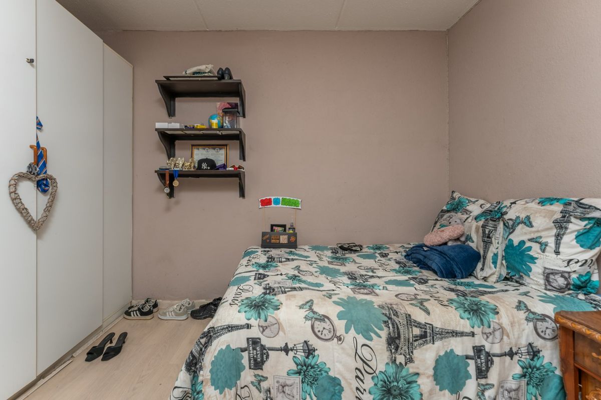 A compact bedroom featuring a built-in wardrobe and neutral wall finishes, offering a functional space ready for personalization.