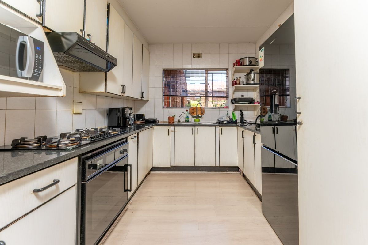 A functional galley-style kitchen featuring built-in cabinetry, a gas hob, an integrated oven, and a tiled backsplash with a window overlooking the exterior.