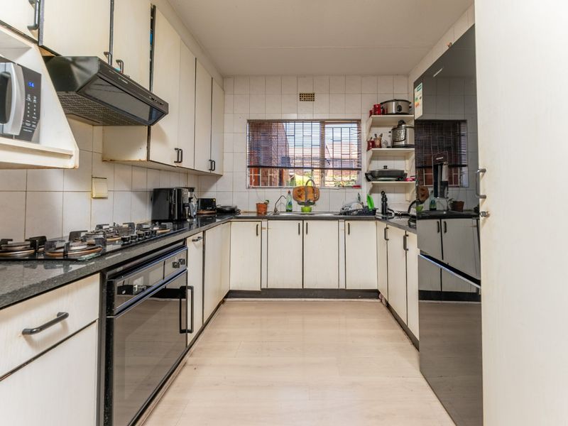 A functional galley-style kitchen featuring built-in cabinetry, a gas hob, an integrated oven, and a tiled backsplash with a window overlooking the exterior.