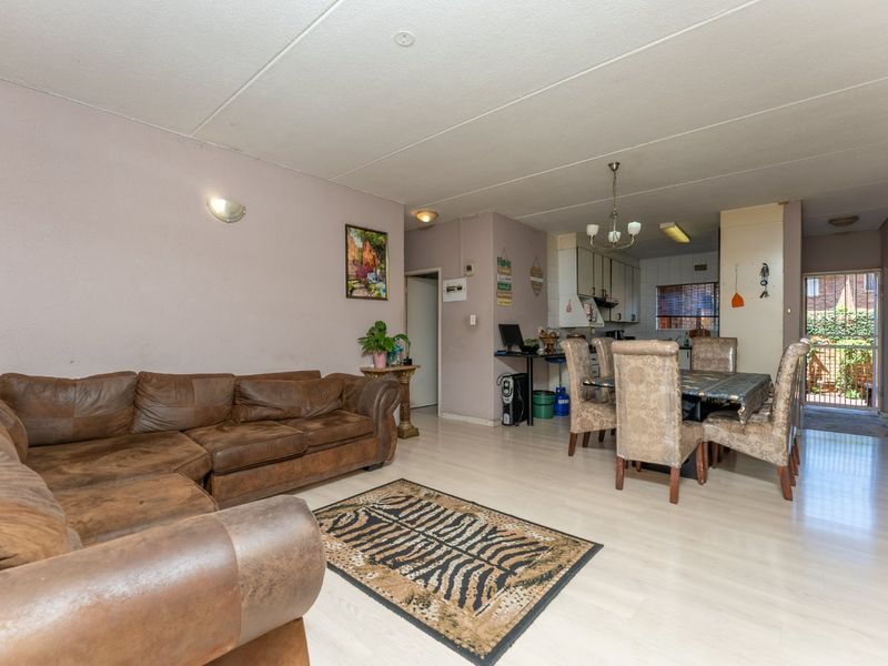 Open-plan living and dining area featuring laminate flooring and direct access to a rear patio area.