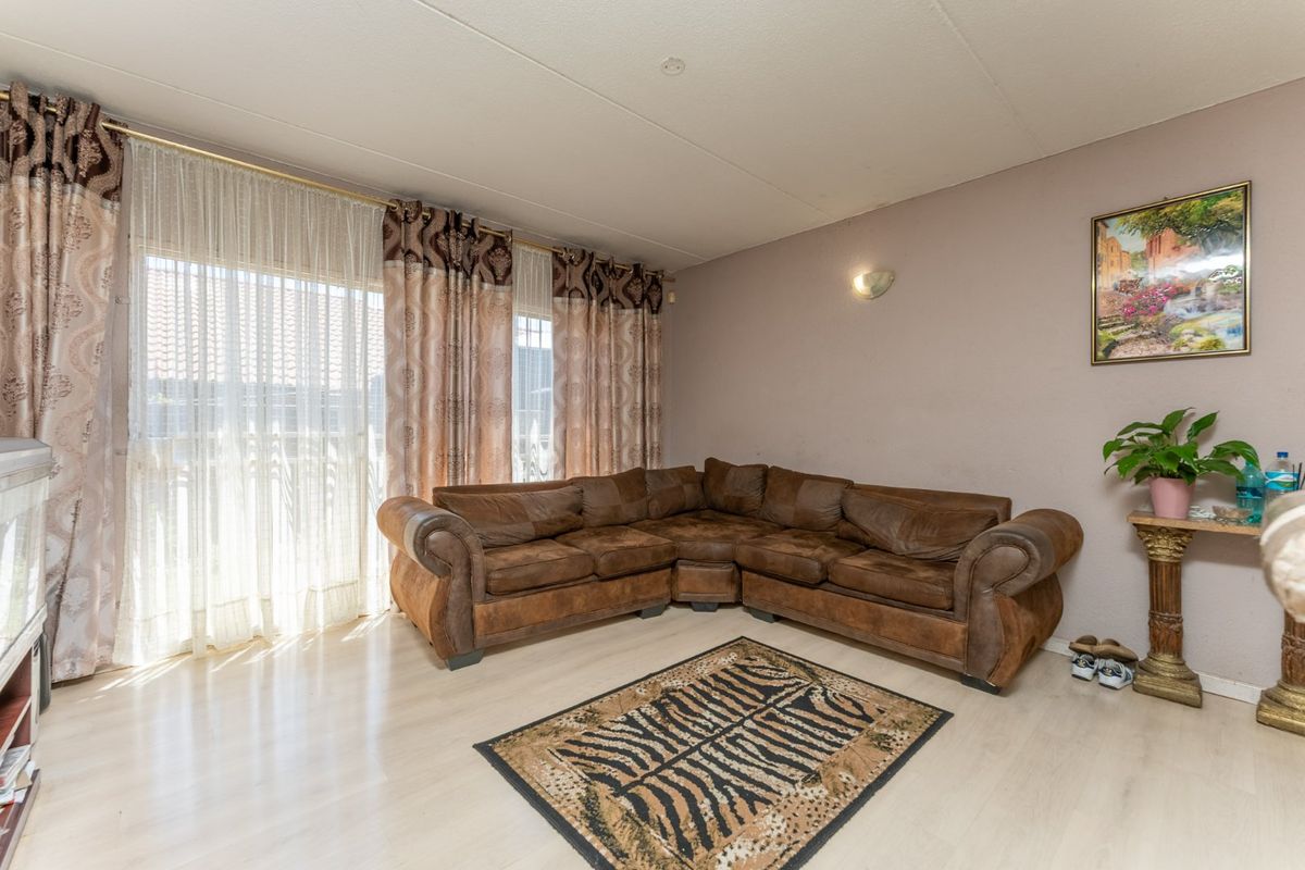 A living room featuring light-toned laminate flooring and a large sliding glass door that provides natural light.