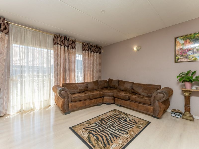 A living room featuring light-toned laminate flooring and a large sliding glass door that provides natural light.