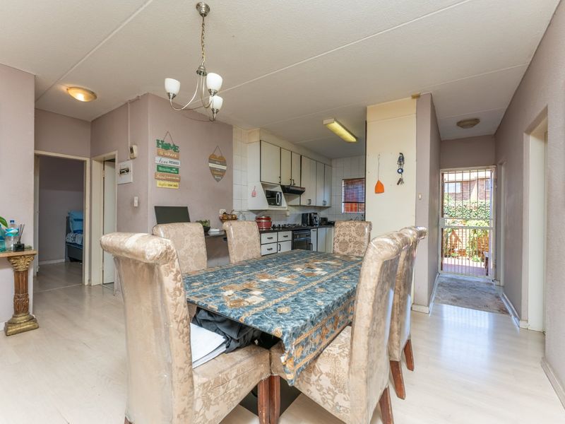 Open plan dining area adjacent to a functional kitchen with built-in cabinetry and direct access to an exterior security gate.