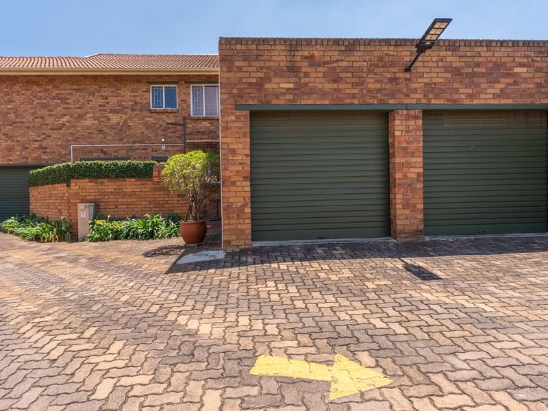 Front view of the townhouse featuring a double garage with roller shutter doors and a paved driveway.