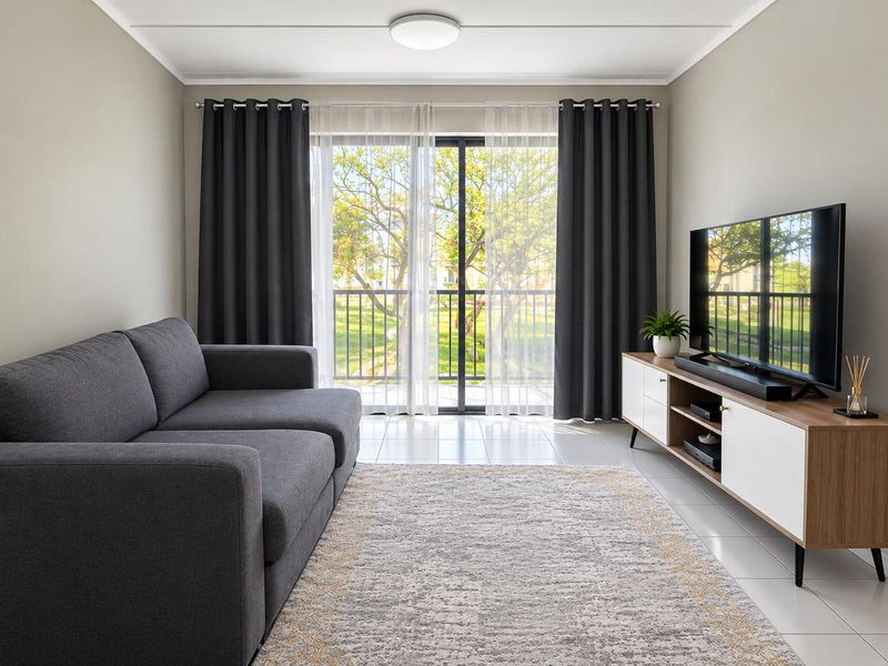 A bright and well-maintained living room featuring tiled flooring, a modern ceiling light, and large sliding glass doors leading to a balcony.