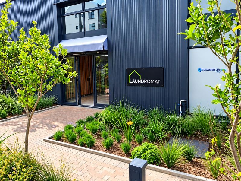 Modern exterior facade featuring dark corrugated metal cladding, a paved entrance walkway, and well-maintained landscaped garden beds.