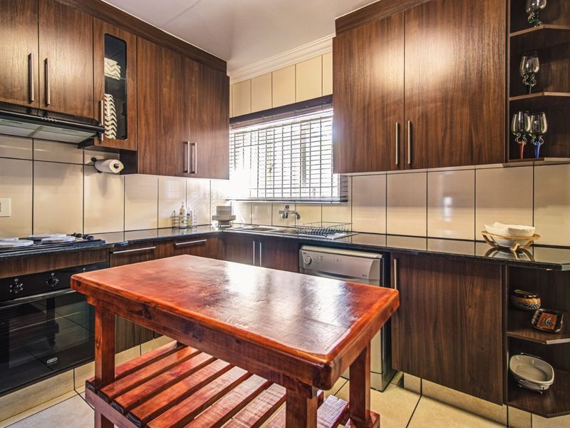 A functional kitchen featuring dark wood cabinetry, granite countertops, a built-in oven with hob, and a tiled backsplash.