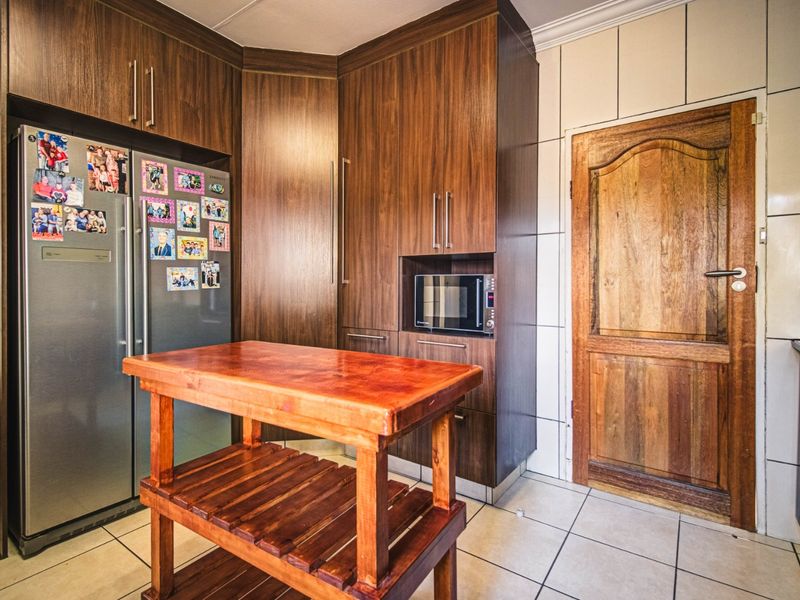 A functional kitchen area featuring dark wood cabinetry, built-in microwave housing, tiled walls, and ceramic floor tiles.