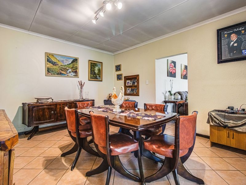 A traditional dining room featuring tiled flooring, coved ceilings, and track lighting, offering a functional space for family meals and entertaining.