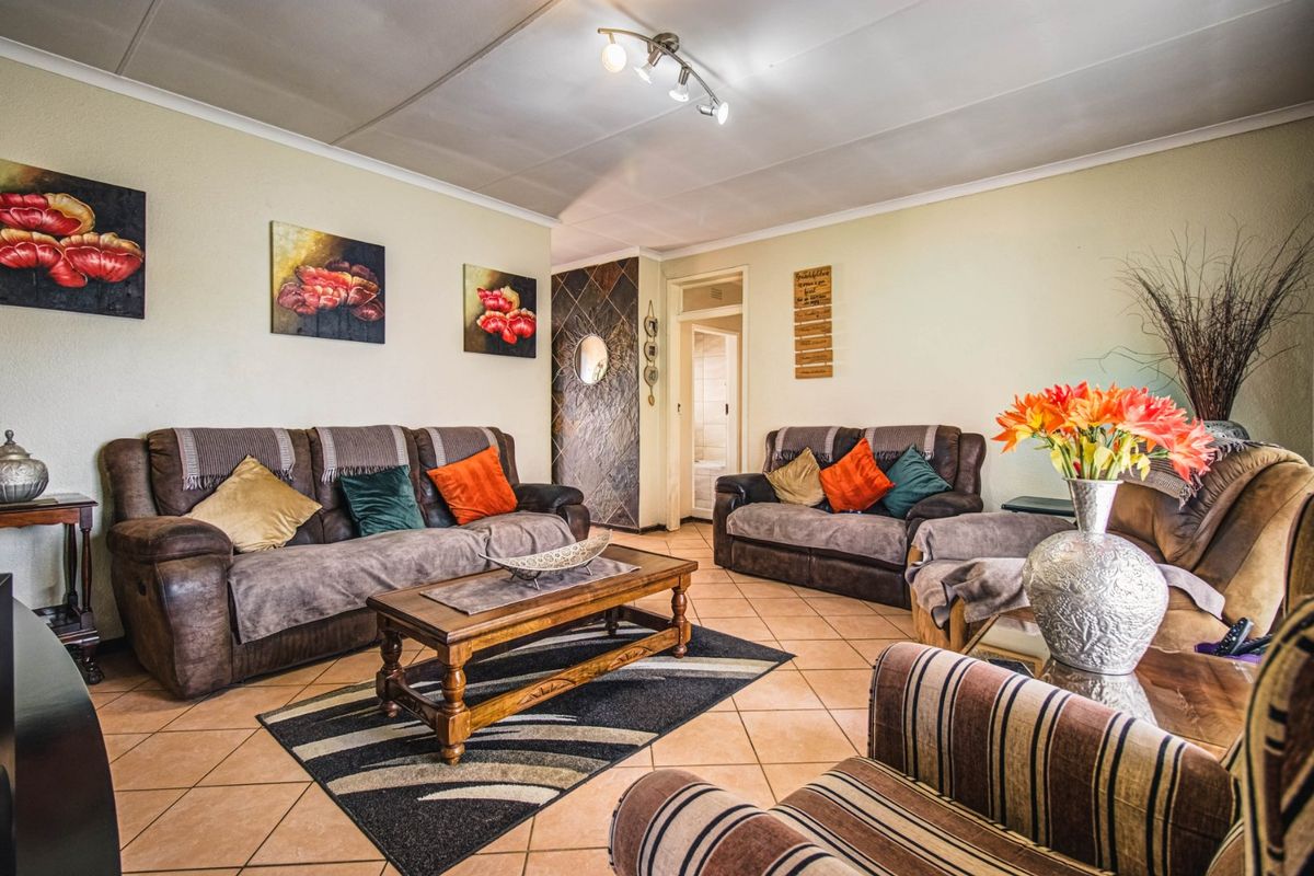 A comfortable living room featuring tiled flooring, a stone-clad feature wall, and modern ceiling spotlighting, offering a warm and inviting atmosphere.