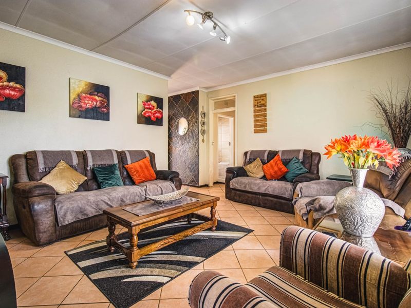 A comfortable living room featuring tiled flooring, a stone-clad feature wall, and modern ceiling spotlighting, offering a warm and inviting atmosphere.