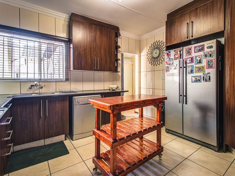 A functional kitchen featuring dark wood cabinetry, granite countertops, tiled backsplash, and tiled flooring, offering a practical layout for daily meal preparation.