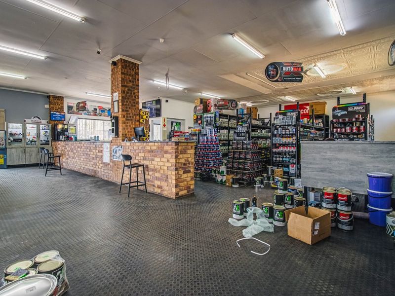 Spacious commercial retail area featuring a brick service counter, durable rubberized flooring, and industrial fluorescent lighting, suitable for automotive or trade supply operations.
