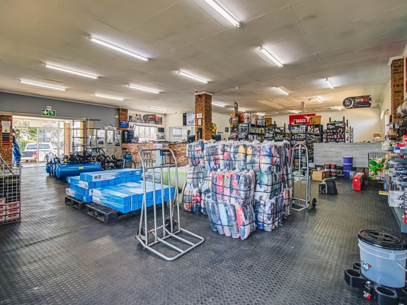 Spacious commercial retail floor featuring durable rubber flooring, exposed brick columns, and functional fluorescent overhead lighting, suitable for automotive or industrial supply operations.