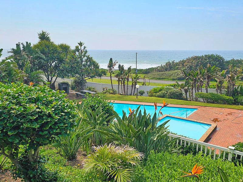 Outdoor pool area featuring a swimming pool, brick paved surround, and landscaped garden with scenic ocean views.