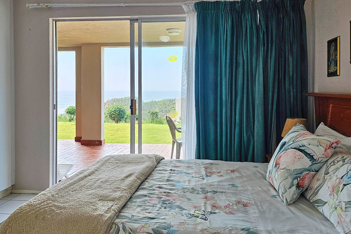 Bedroom featuring tiled floors, built-in wardrobe, and sliding glass doors opening onto a covered patio with garden and sea views.