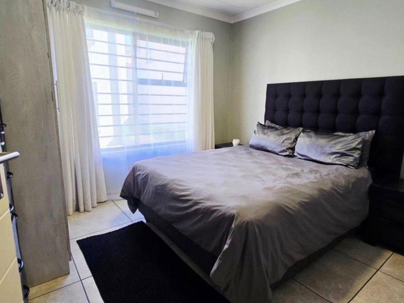 A well-maintained bedroom featuring neutral wall tones, tiled flooring, and a built-in cupboard, offering a clean and functional living space.
