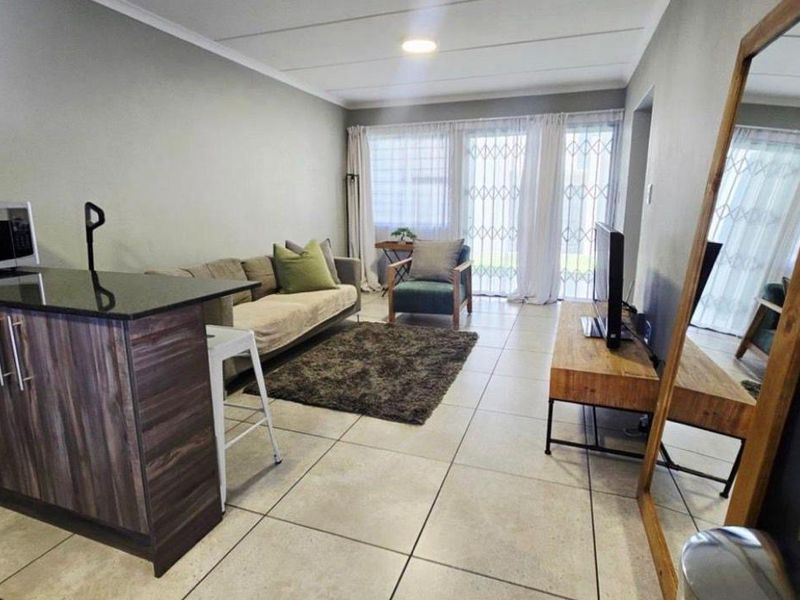 An open-plan living area featuring tiled flooring, a kitchen island with granite countertops, and sliding glass doors leading to an outdoor space.