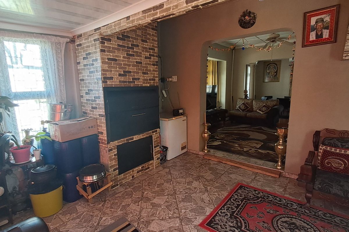 Living area featuring a built-in brick fireplace, tiled flooring, and an arched transition to an adjacent room.