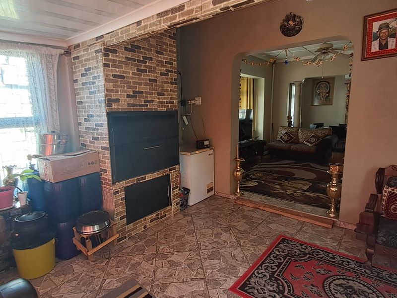 Living area featuring a built-in brick fireplace, tiled flooring, and an arched transition to an adjacent room.