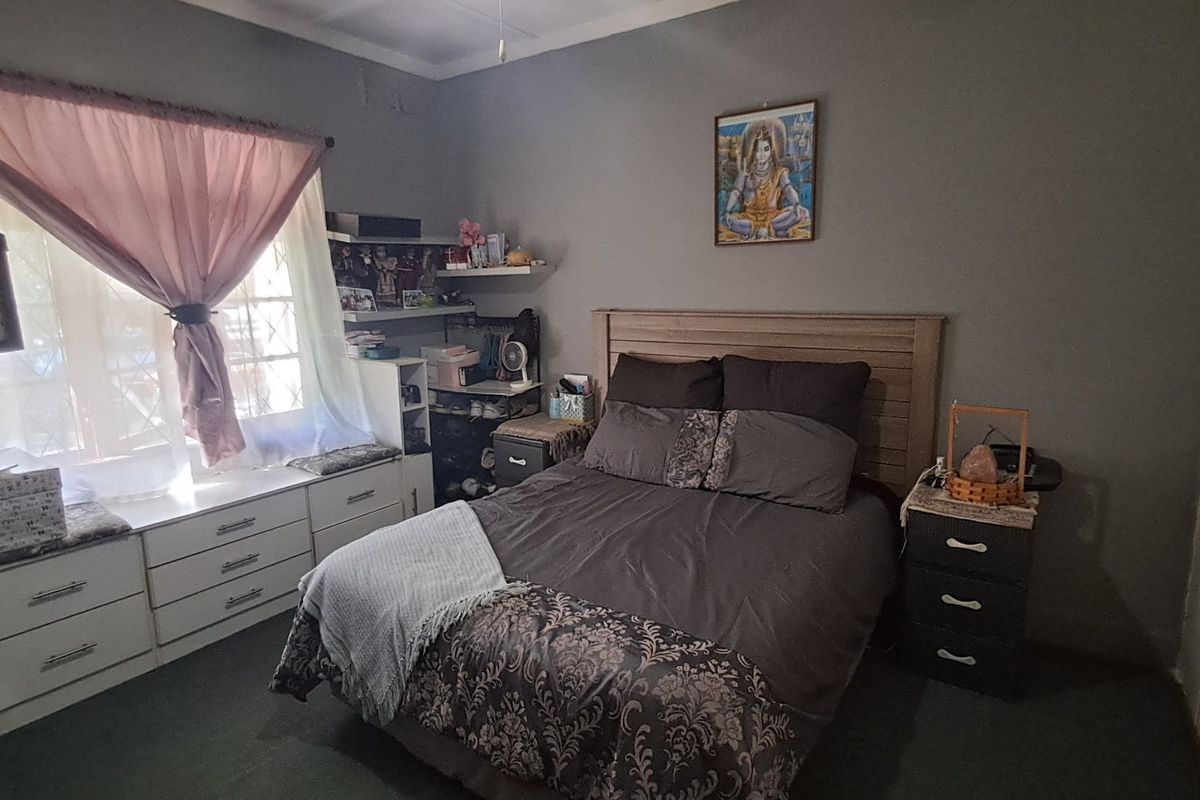 A functional bedroom featuring built-in cupboards and a window seat with security bars, offering practical storage and a comfortable layout.