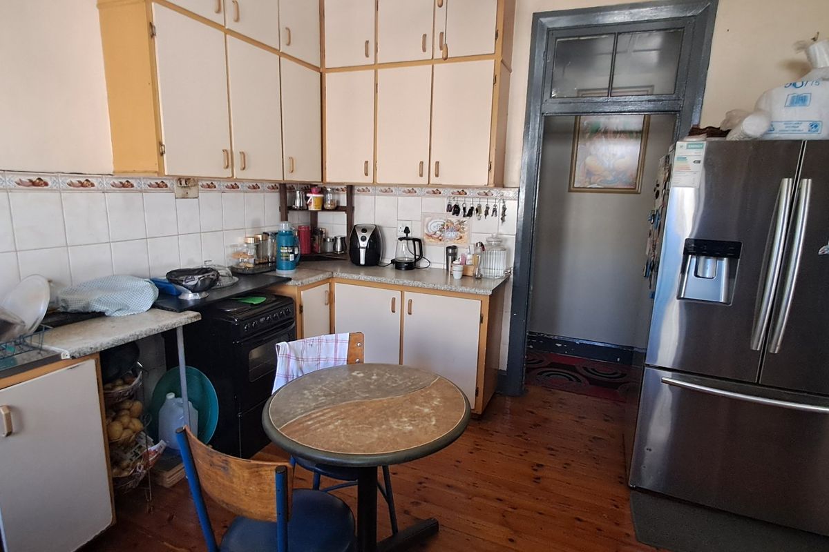 A dated kitchen featuring original cabinetry, tiled backsplash, and hardwood flooring, offering potential for a modern renovation to enhance functionality and aesthetic appeal.