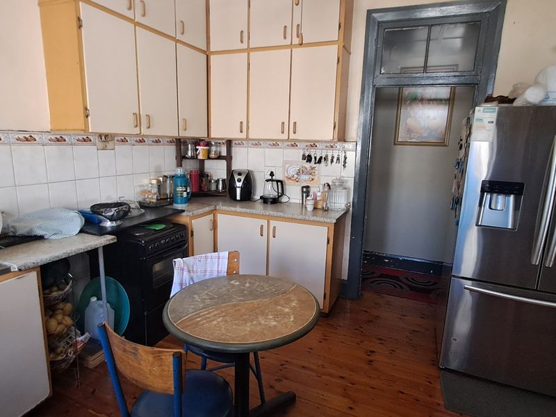 A dated kitchen featuring original cabinetry, tiled backsplash, and hardwood flooring, offering potential for a modern renovation to enhance functionality and aesthetic appeal.