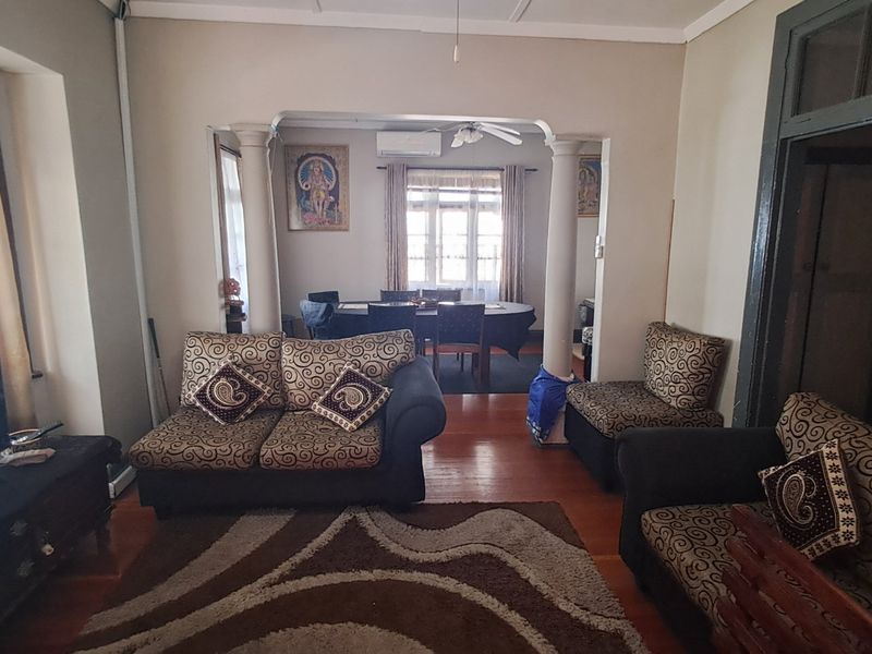 Open-plan living and dining area featuring hardwood flooring, decorative columns, and a split-system air conditioner, offering a functional layout for family living.