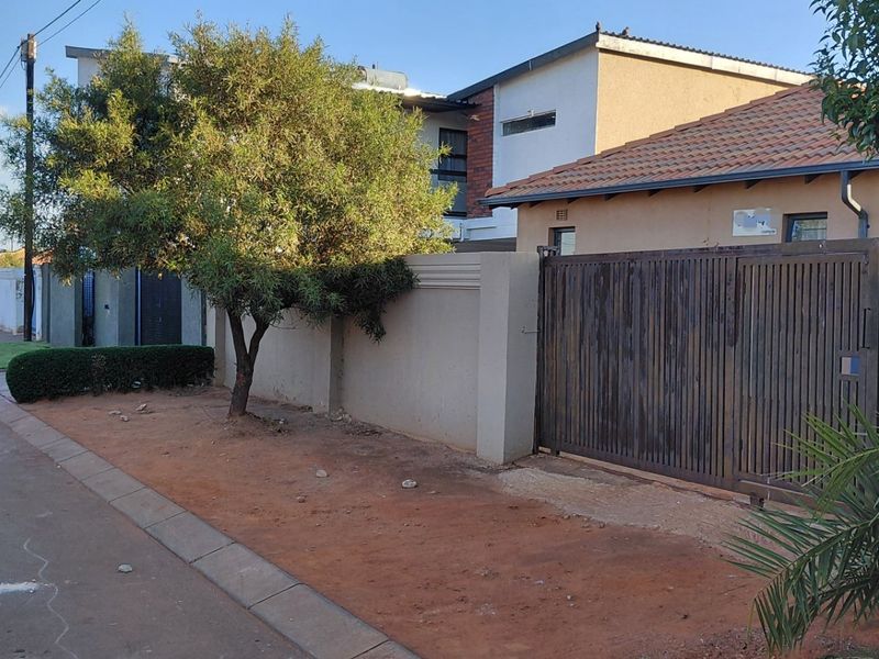 Front exterior view of the property featuring a perimeter wall, sliding gate, and tiled roof structure.