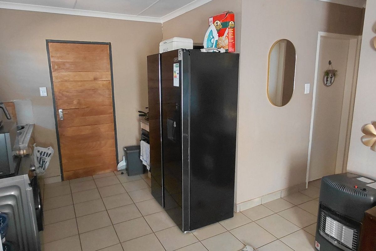 A functional kitchen area featuring tiled flooring and a wooden door, providing a practical layout for daily use.