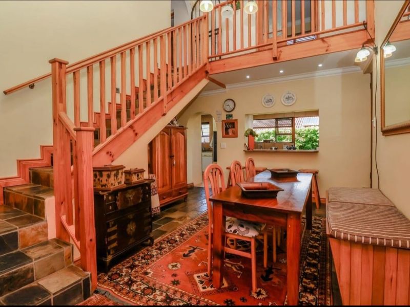 Dining area featuring slate tile flooring, a wooden staircase with balustrade, and a pass-through window connecting to the kitchen area.