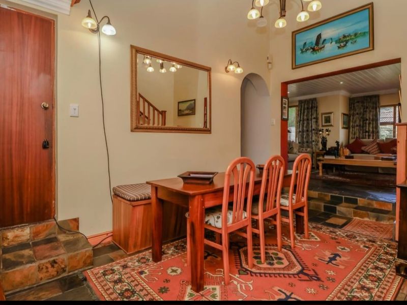 Dining area featuring stone tile flooring, an arched entryway leading to the living space, and a staircase with wooden railings.