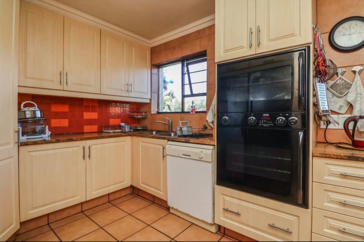 A functional kitchen featuring cream cabinetry, granite countertops, a double eye-level oven, and tiled finishes, offering a classic layout with ample storage space.