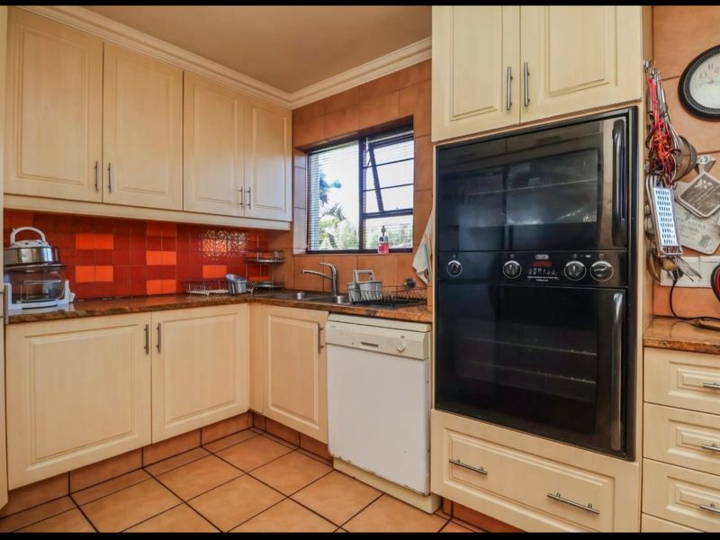 A functional kitchen featuring cream cabinetry, granite countertops, a double eye-level oven, and tiled finishes, offering a classic layout with ample storage space.