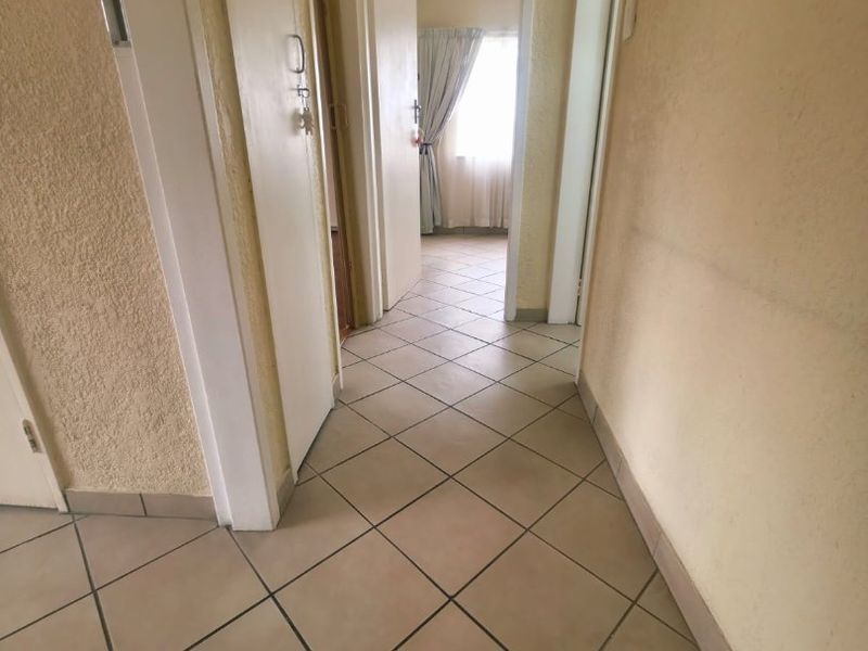 A functional hallway featuring neutral tiled flooring and access to multiple rooms, providing a clean canvas for potential interior updates.