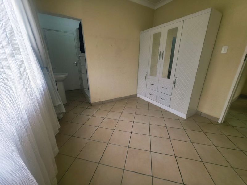 A bedroom featuring tiled flooring and direct access to an en-suite bathroom, offering a functional layout with neutral wall finishes.