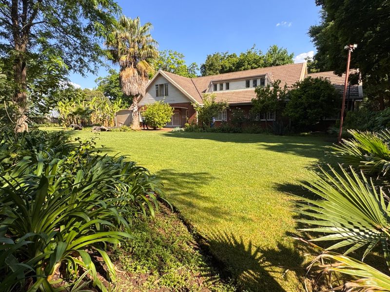 A view of the rear elevation of the house featuring a well-maintained lawn and established garden.