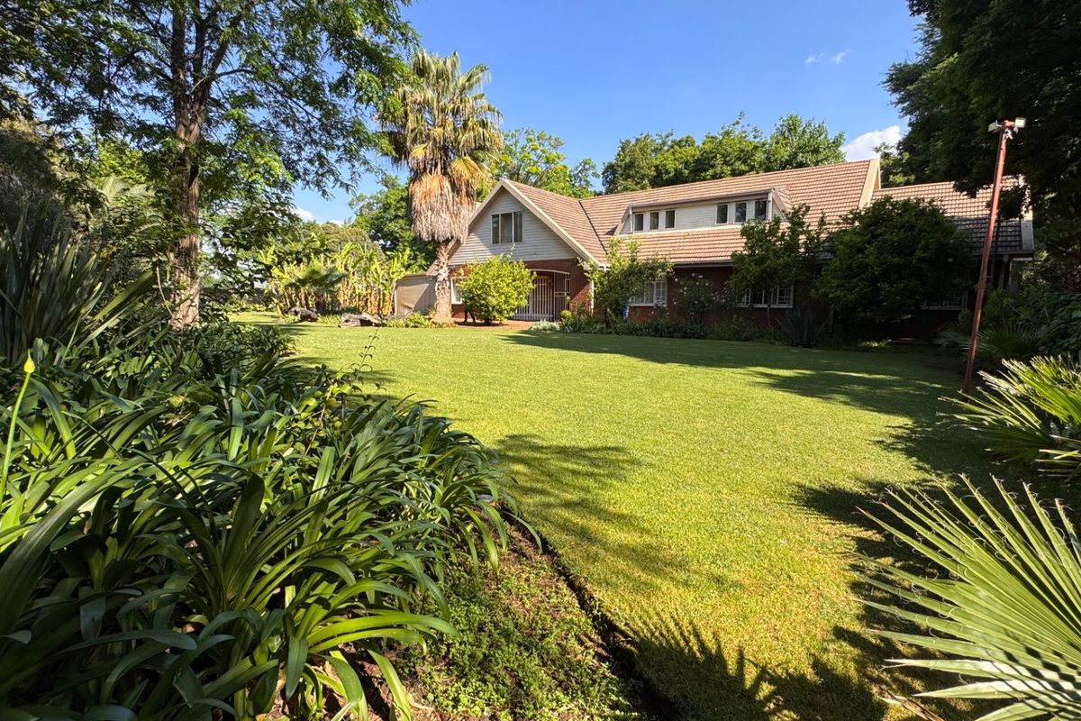 A spacious rear garden featuring a well-maintained lawn and mature landscaping, providing a private outdoor setting for the brick-clad residence.