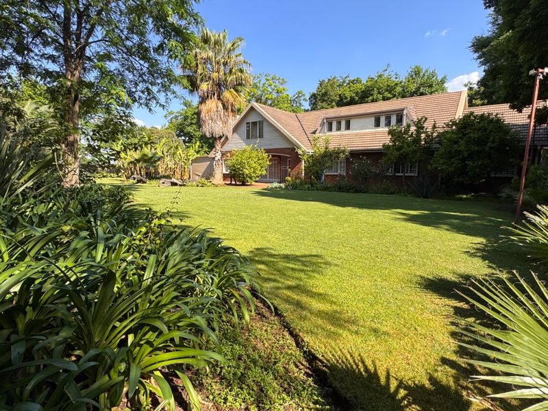 A spacious rear garden featuring a well-maintained lawn and mature landscaping, providing a private outdoor setting for the brick-clad residence.
