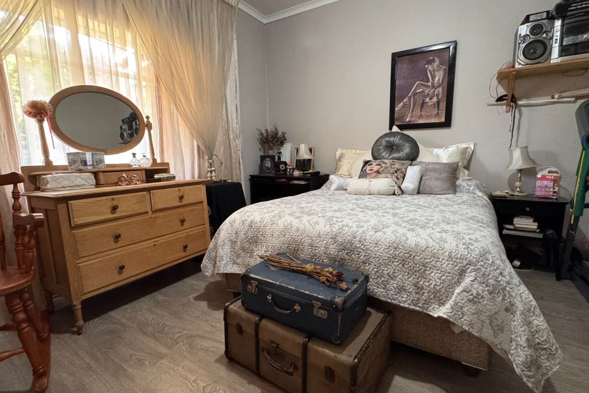 A cozy bedroom featuring laminate flooring and large windows with curtain rails, offering a comfortable and functional living space.
