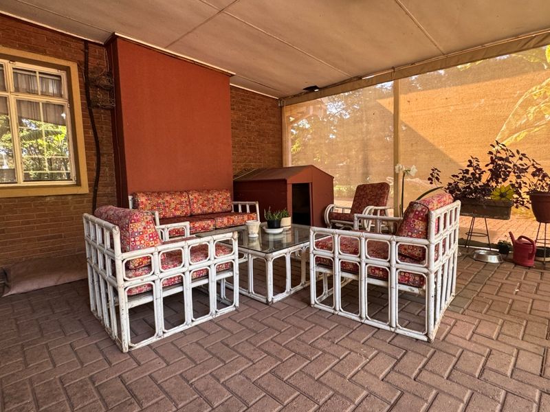 A covered outdoor patio area featuring brick paving and a brick wall, providing a functional space for outdoor relaxation.