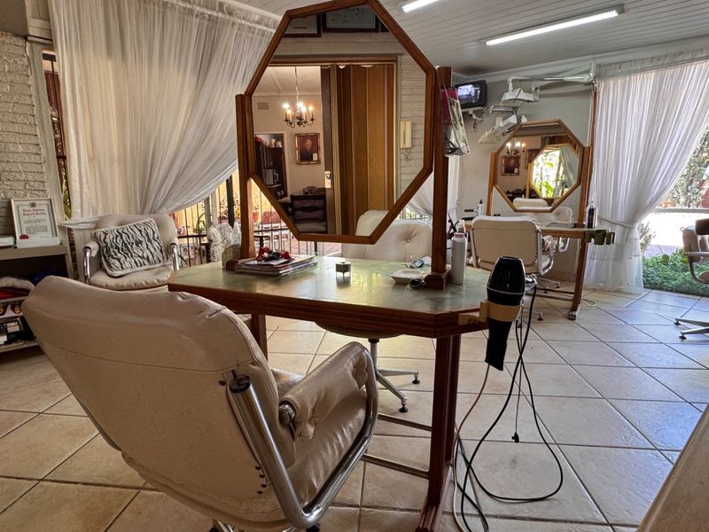A commercial salon space featuring tiled flooring, exposed brick walls, and multiple styling stations with mirrors.