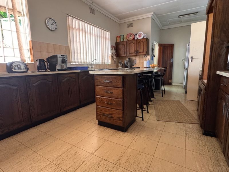 A functional kitchen featuring traditional wooden cabinetry, a central island, tiled flooring, and ample counter space, offering potential for a modern renovation.